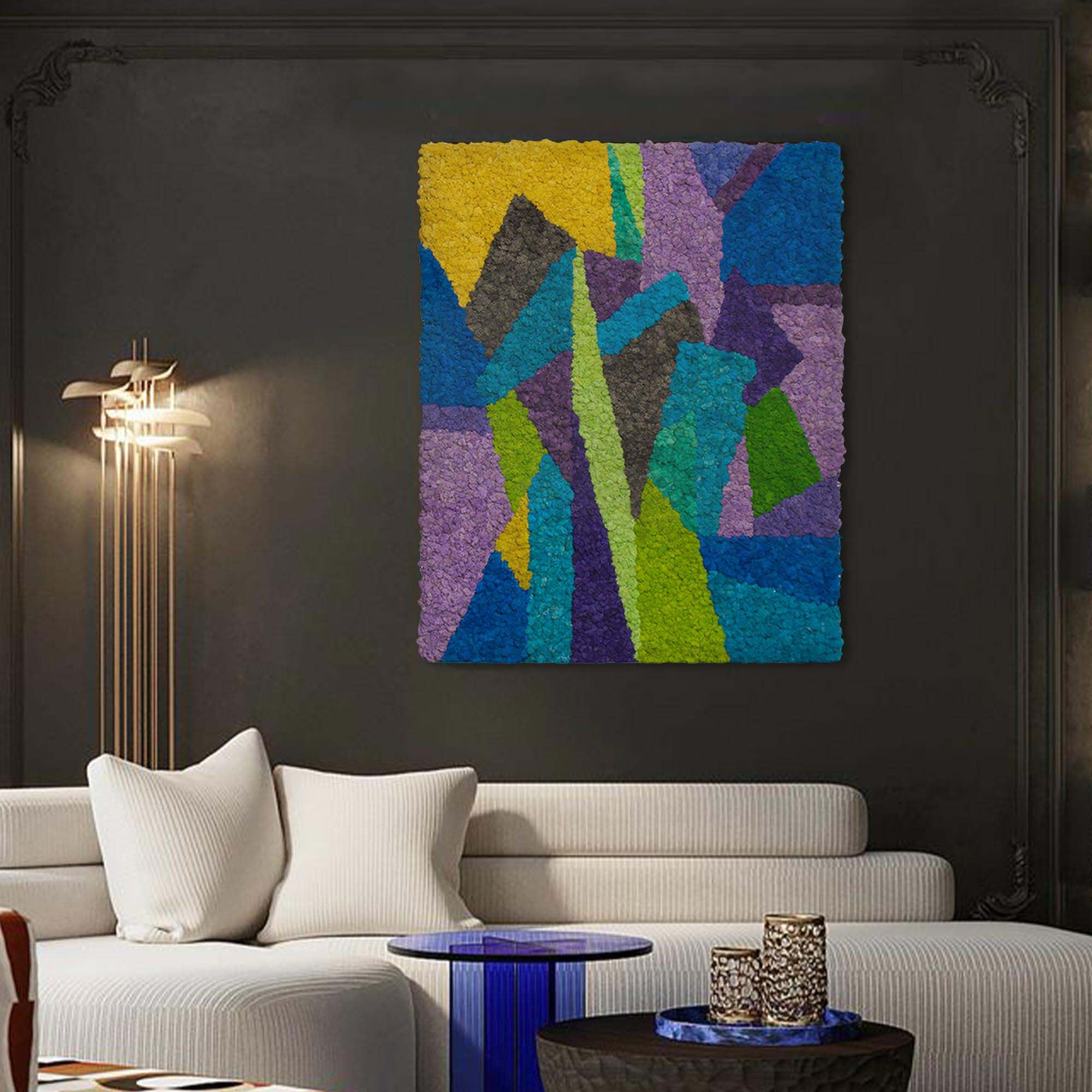 Modern abstract reindeer moss wall art in cool blue, purple, and yellow tones hangs above a cream sofa, complemented by modern lighting.