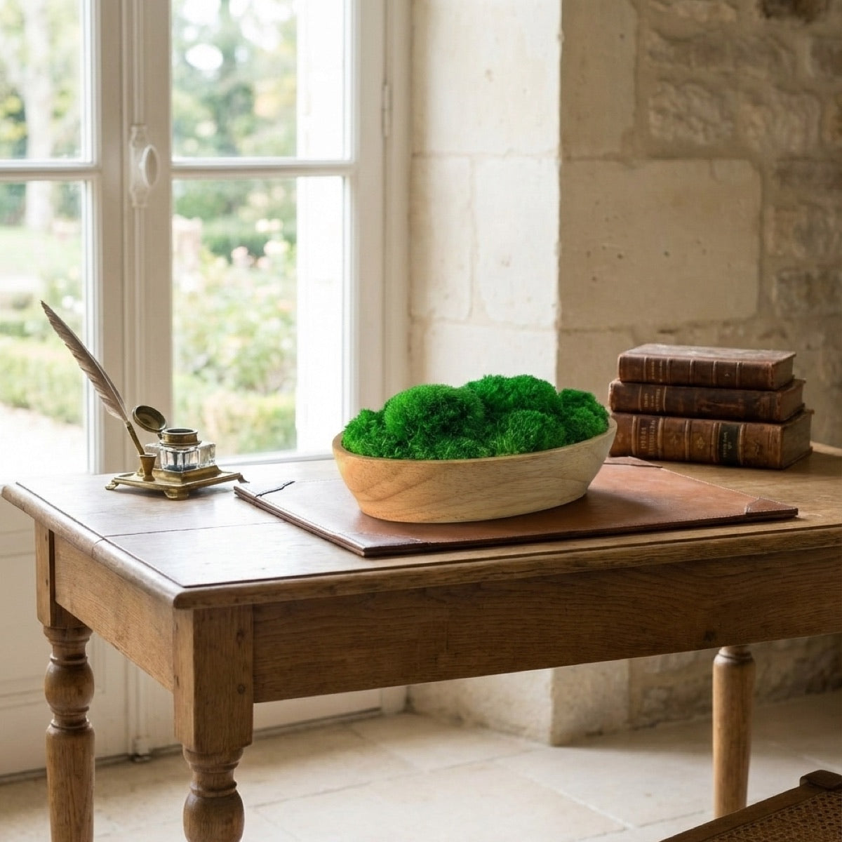 Boat shape wood moss bowl with preserved green moss styled on a vintage wooden desk, natural tabletop decor for home or office interiors.