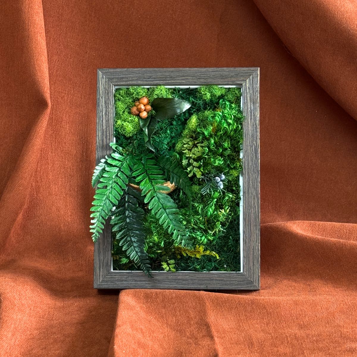 Front view of Lush Moss Table Frame in walnut with mixed preserved moss, photographed on an orange fabric backdrop.